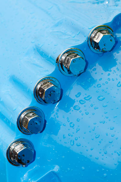 Close up image of chromed nuts and bolts on a construction equipment. Detail of water droplets on blue paint