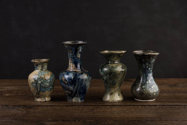 istock Four small marble vases on wooden table with black beckground 1127804381