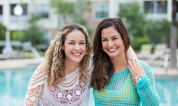 istock Hispanic sisters smiling by swimming pool 1127805590