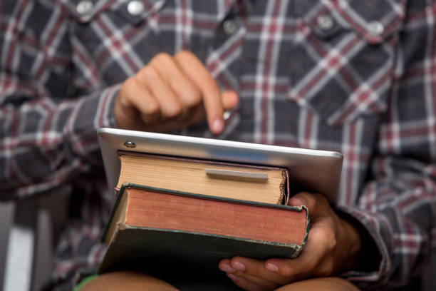 istock Boy holds books and tablet, focus on book and hand 1127807536