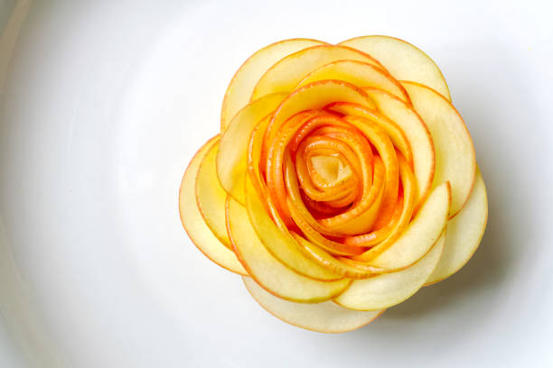 Rose carved from apple Rose carved from apple, on white porcelain - top view close up, selective focusing carving fruit stock pictures, royalty-free photos & images