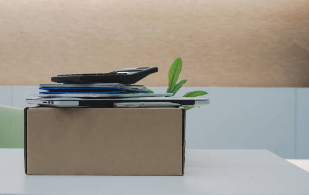 close up on tan box carton with group of object such as laptop ,tablet, calculator and calendar lay on the top at office table after cleaning and prepare for move , work concept - group of objects business human resources laptop imagens e fotografias de stock