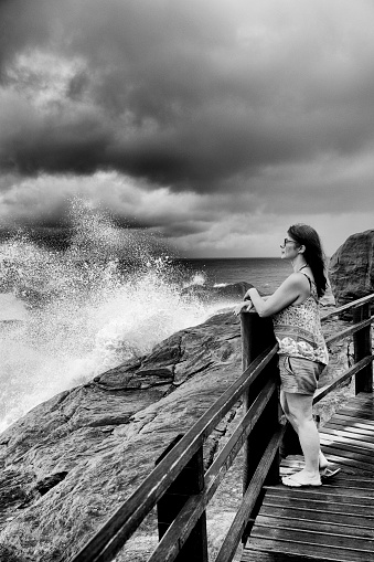 Middle-aged woman with a serene expression watches the sea during the arrival of a storm on the southeastern coast of Brazil