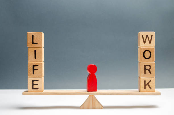 istock Red human figure between the words life and work on the scales. choice between life and work. The concept of paying attention to the life values, promotion at work, overtime and exhausting work. 1127812547