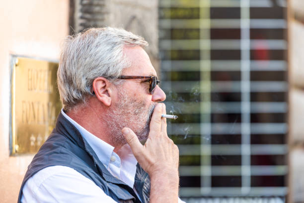 Closeup Of Senior Man Grey Hair Holding Cigarette Smoke In Hand During Day  On Street Unhealthy Smoking Stock Photo - Download Image Now - iStock