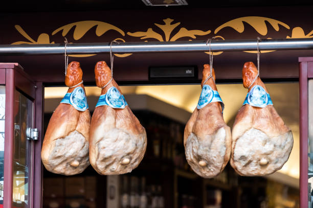 zbliżenie szynki parma prosciutto wiszące na sznurku na wystawie w sklepie z rzeźnikiem w tle wejścia do sklepu - 11313 zdjęcia i obrazy z banku zdjęć