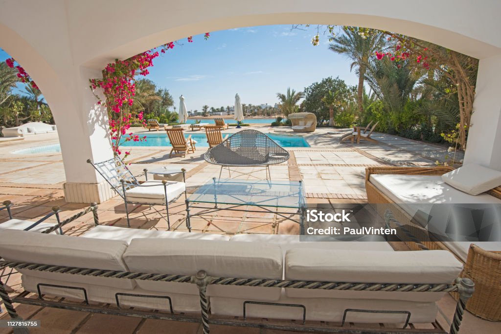 Swimming pool and outdoor seating area at a luxury tropical holiday villa Luxury villa show home in tropical summer holiday resort with swimming pool and sun chairs outdoor furniture Architecture Stock Photo