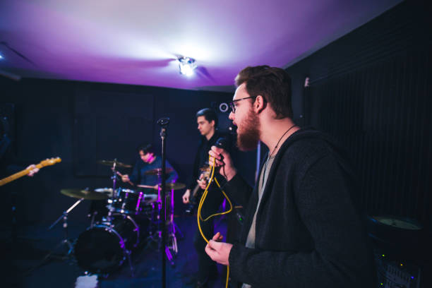 istock Male singer with microphone and rock and roll band 1127816783