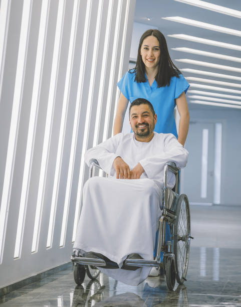 nurse pushing wheelchair with patient in hospital - therapy people cheerful looking at camera imagens e fotografias de stock