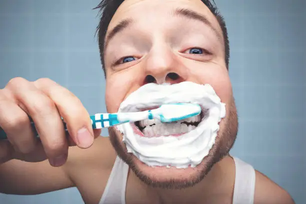 Photo of Funny portrait of a man brushing his teeth