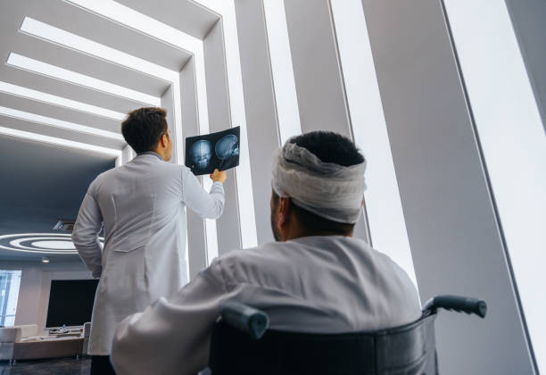 Young doctor man looking x-ray of the patient's skull Healthcare professional young doctor examining and  analyzing x-ray CT Scan test of human head results of the patients skull with his patient in a medical hospital clinic. bandage stock pictures, royalty-free photos & images