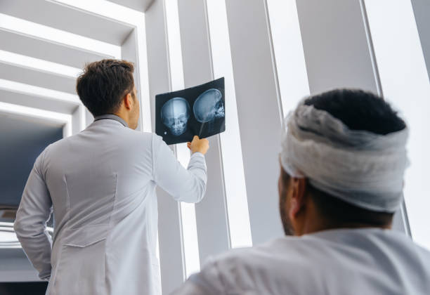 giovane medico che guarda la radiografia del cranio del paziente - doctor brain x ray x ray image foto e immagini stock
