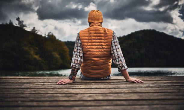 Tourist Enjoying moments of silence  sitting on the pier in the mountains