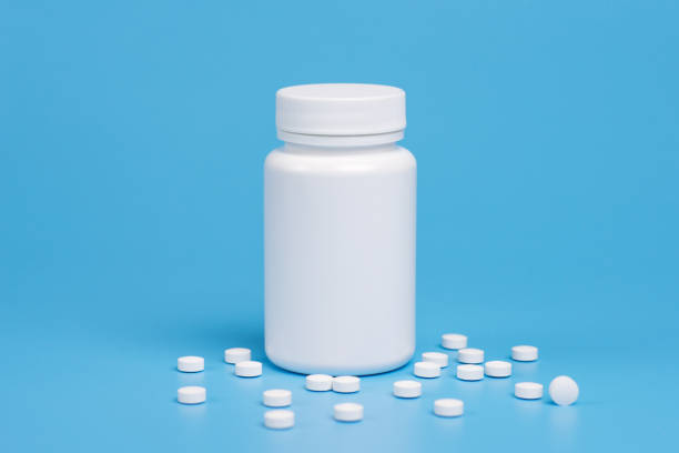 istock White pills, tablets and white bottle on blue background. Copy space for text 1127829053