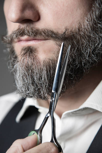 close up of a barber adjusting his mustache with a pair of scissors stock photo