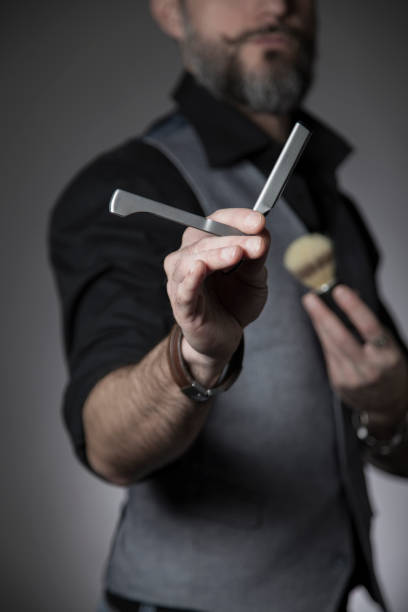 barber showing a straight razor in the foreground stock photo