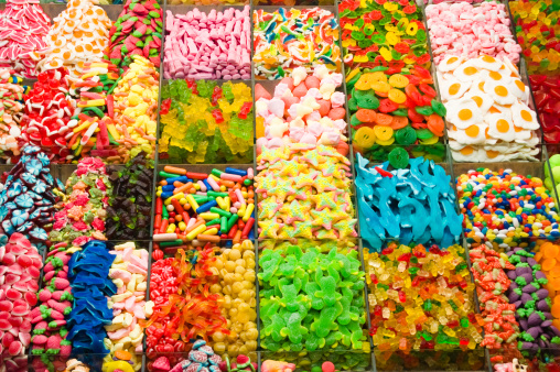 A large selection of candy in a vendor stall including gummy bears, sweets,star shapes,egg shaped candy.