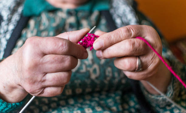istock Old woman knitting in home near the window. Selective focus 1127833621