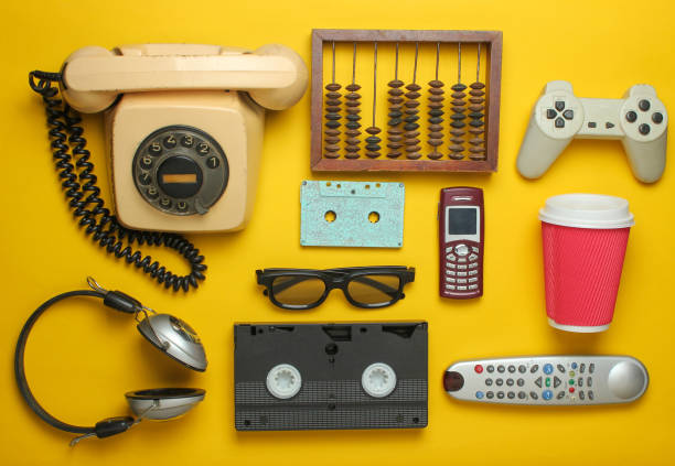 retro objects on a yellow background. rotary telephone, audio cassette, video cassette, gamepad, 3d glasses, tv remote, headphones, push-button phone. analog media technology of the past. flat lay - video cassette tape imagens e fotografias de stock