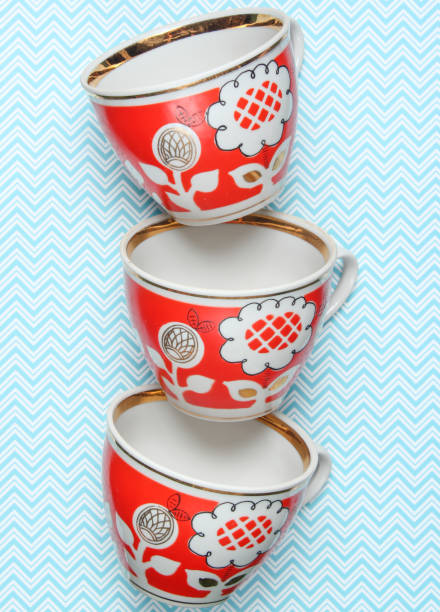 stapel von retro-cups mit rotem muster auf einer tischdecke - old fashioned tea cup victorian style beauty stock-fotos und bilder