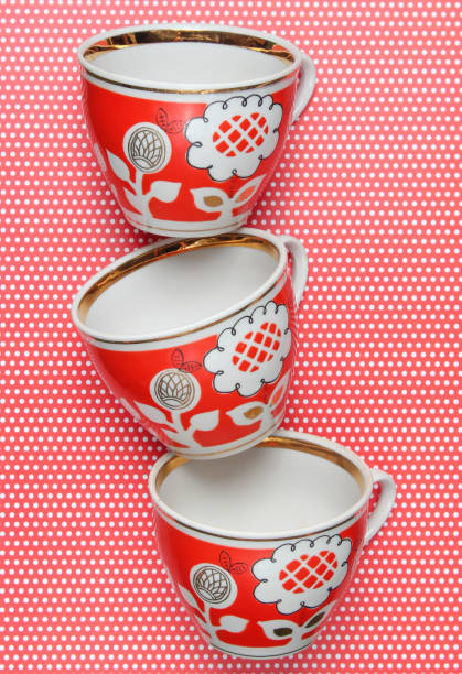 stapel von retro-cups mit rotem muster auf eine tischdecke mit tupfen - old fashioned tea cup victorian style beauty stock-fotos und bilder