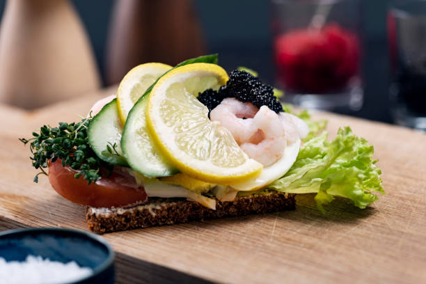 Traditional Danish open sandwich or Smørrebrød Smørrebrød is a traditional open faced sandwich made with dark rye bread with various cold toppings. Toppings range from egg, smoked fish to cold meats with various pickles and herbs added. Traditionally eaten at lunchtime or occasionally at the end of a party. Egg with prawn and caviar, colour, horizontal with some copy space. danish culture photos stock pictures, royalty-free photos & images