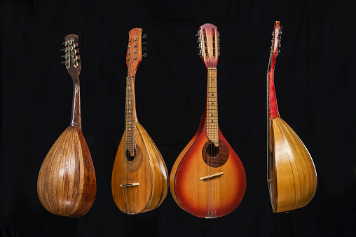 Four different mandolins isolated on dark background.