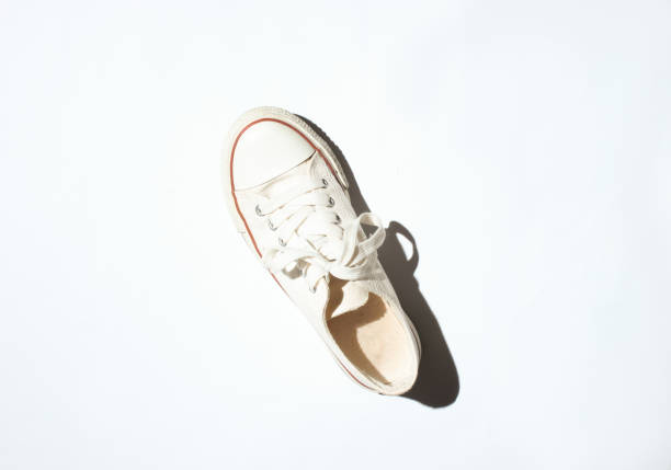 istock Fashionable white sneaker on white background. Photo with shadows, hard light, top view 1127836765