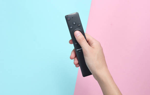 Female hand holds the TV remote stock photo