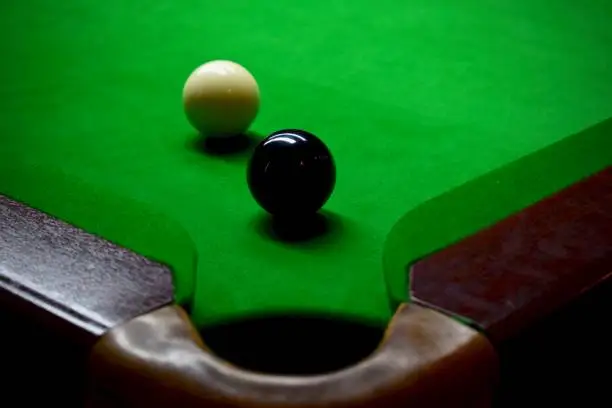 Snooker balls on a green table in front of the pocket ready to play