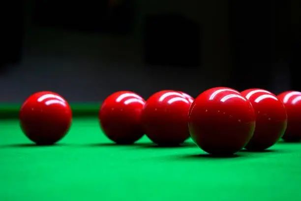 A group/pack of red snooker balls lying on a green billard table