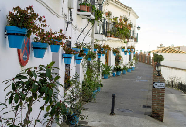 A small street in Mijas, Spain with many hanging baskets filled with flowers. A small street in Mijas, Spain with many hanging baskets filled with flowers. mijas pueblo stock pictures, royalty-free photos & images