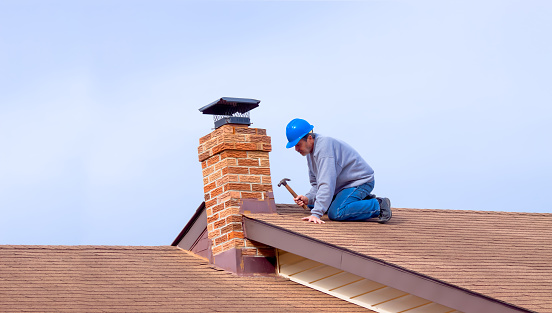 Contractor Builder with blue hardhat repaoiring roof