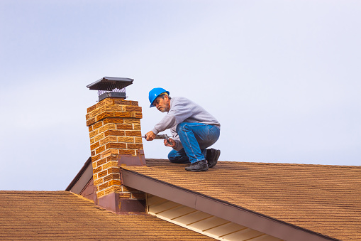 Contratista constructor con casco azul sobre la chimenea de sellado de techo photo