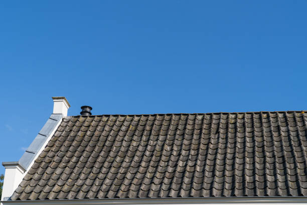 istock Roof with grey roof tiles and a clear blue sky with some clouds on a sunny day 1127846607
