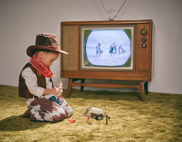 Vintage TV and Little Boy Cowboy A period correct 1960's television displaying a cowboy scene on the screen (not simulated) with a little boy dressed as a cowboy watching the screen. Image toned to match the era. shag rug stock pictures, royalty-free photos & images