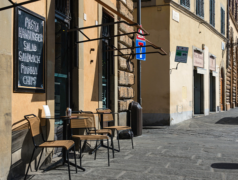 A cozy restaurant with chairs and tables on the sidewalk sidewalk in downtown Florence, Italy.