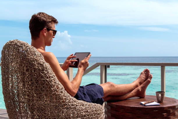 istock young man in swimsuit working on a tablet in a tropical destination 1127857261