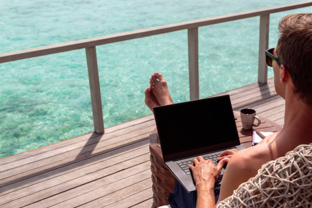 istock young man in swimsuit working on a laptop in a tropical destination 1127857435