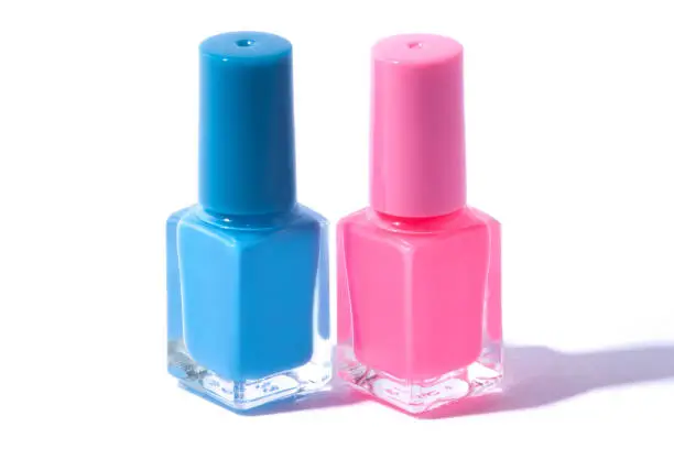 Photo of Blue and pink nail polish bottles isolated on a white background.