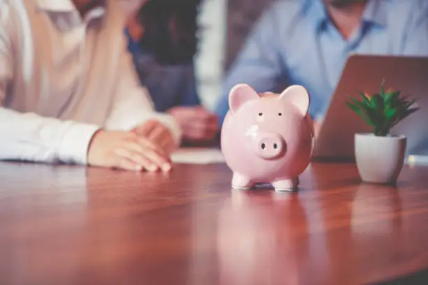 Business people with a piggy bank. There are three business people of different ethnic groups. All are happy and smiling. All are dressed in business casual clothing.
