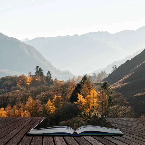 Beautiful Autumn Fall landscape image of the view from Catbells in the Lake District with vibrant Fall colors being hit by the late afternoon sun coming out of pages of open story book stock photo