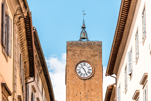 Orvieto, Italy Italian outdoor empty street in Umbria historic city town village road narrow alley with orange walls church clock tower closeup
