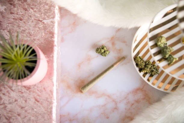 Top Down View of Marijuana Joint and Bud on Pink Marble Vanity Luxury Cannabis stock photo