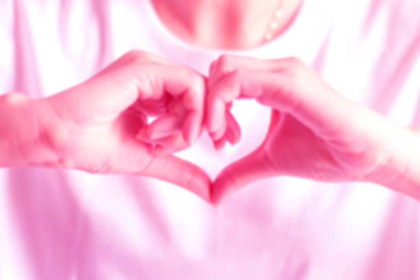 Blurry image of hand signs to be heart shape; showing love in pink color tone photo. Blurry pink tone image of a person join two hands to be a heart to gesture of love; hand signs of love. pollex stock pictures, royalty-free photos & images