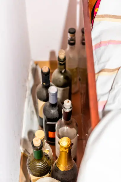 Many dusty old wine and champagne bottles with corks by bed in alcoholic home house in rustic cottage farm house home cabin dacha closeup
