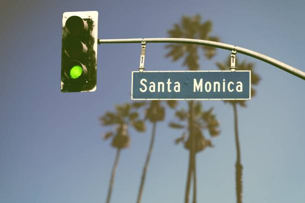 Retro styled Santa Monica Boulevard road sign with green traffic light and de-focused palm trees in background
