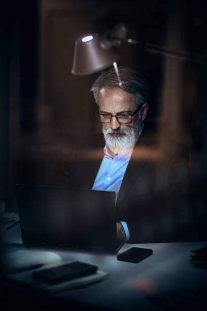 istock businessman in office  working on laptop at night 1127884956