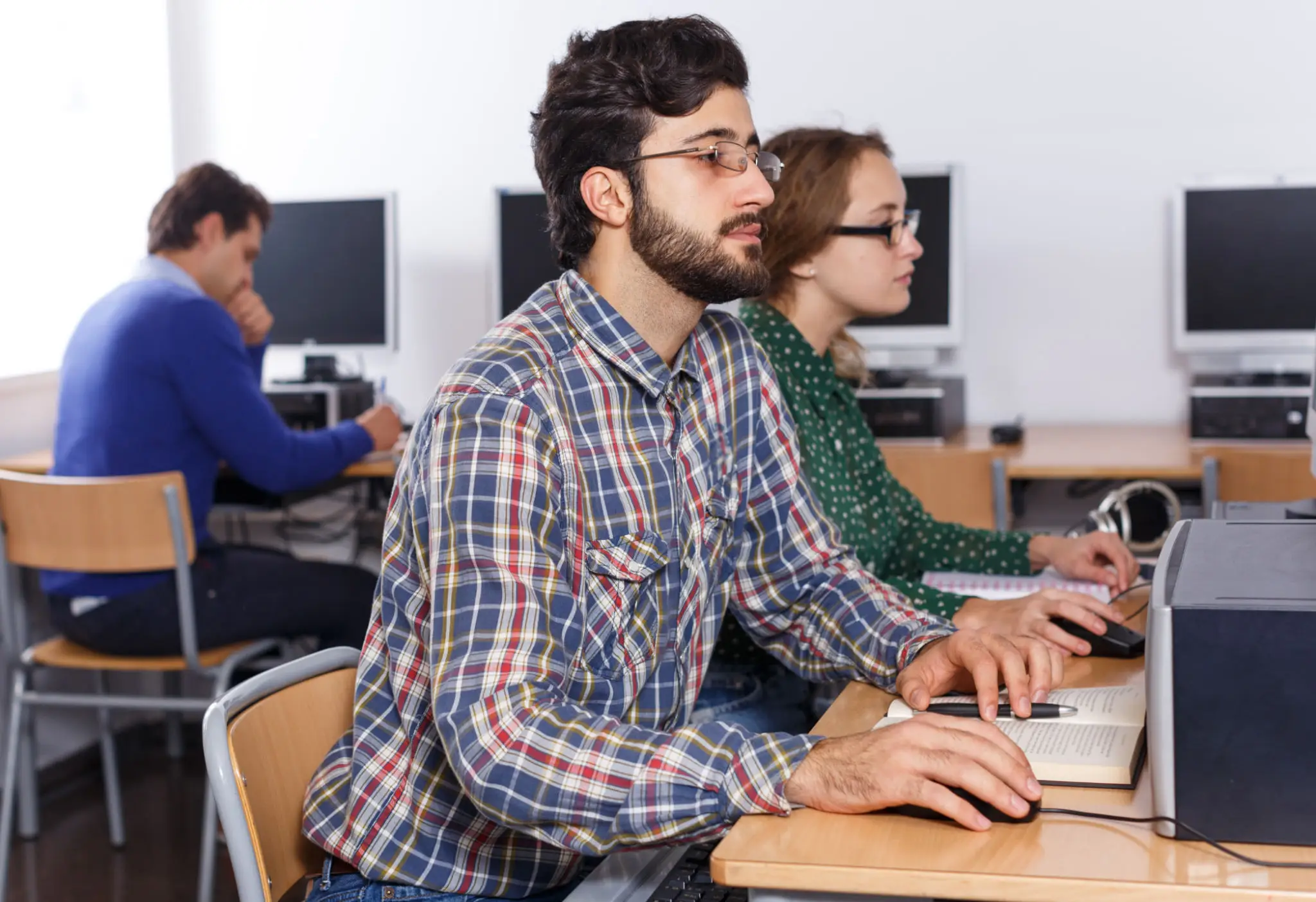 Man working with computer and books in library