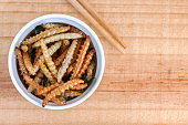 Bamboo edible worm insects crispy or Bamboo Caterpillar in white bowl on a wood table. The concept of protein food sources from insects. It is a good source of protein, vitamin, and fiber.